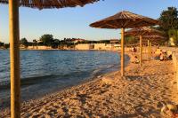 a beach with umbrellas and people sitting on the sand at Apartments with a parking space Bibinje, Zadar - 5753 in Bibinje