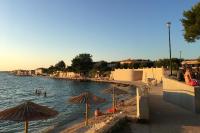 a beach with umbrellas and people in the water at Apartments with a parking space Bibinje, Zadar - 5753 in Bibinje