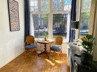 ein Wohnzimmer mit Tisch und Stühlen und einem Fenster in der Unterkunft Canal Hideaway in Amsterdam