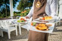 una persona sosteniendo tres platos de comida en una mesa en Strandhotel Glücksburg, en Glücksburg