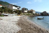 a boat sitting on the shore of a beach at Apartments with a parking space Komiza, Vis - 12325 in Komiža