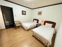 a room with two beds and a chair in it at Abbo Hotel in Tainan