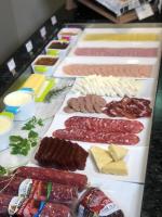 een tafel met verschillende soorten vlees en kaas bij Aquarius Hotel Flat Residence in Santa Cruz do Sul