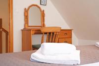 a bed with a chair and a dresser with a mirror at Lescoat-le petit paradis in Plestin-les-Grèves