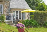 a yellow umbrella and flowers in front of a house at Lescoat-le petit paradis in Plestin-les-Grèves