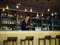 Un hombre parado detrás de una barra en una habitación. en Hôtel de Cavoye, en Fontainebleau