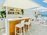 a bar with white bar stools and a view of the ocean at Hotel Apartamentos Marina Luz in Chipiona
