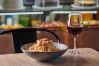 a bowl of pasta and a glass of wine on a table at Ibis Torreon in Torreón