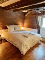 a bedroom with a large white bed with a wooden wall at Manoir du Suquet in Bardou