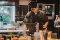 a man in a kitchen preparing food at Das Schokoladenhotel in Westerstede