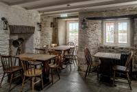 a restaurant with tables and chairs in a room with stone walls at The Olde Malthouse Inn in Tintagel