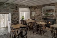 a restaurant with wooden tables and chairs and a fireplace at The Olde Malthouse Inn in Tintagel