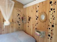 a bedroom with a wooden wall with a bed and a mirror at Echappée sauvage in Masquières