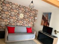 a living room with a stone wall and a couch at Studio indépendant Lisieux in Lisieux