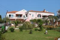 une maison rose avec un chien dans la cour dans l&#39;établissement Apartments by the sea Sukosan, Zadar - 5905, à Sukošan