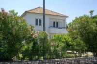 a white house behind some trees and a fence at Family Room Drace 4550a in Drače