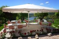 a table and chairs under a large white umbrella at Logis Hôtel Beau Site in Loubaresse