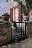 a gate with two potted plants in front of a window at La Petite Maison in Beynac-et-Cazenac