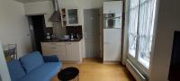 a living room with a blue couch and a kitchen at Appartement coquet sur les hauteurs de Montmartre in Paris