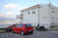 une voiture rouge garée dans un parking à côté d&#39;un bâtiment dans l&#39;établissement Apartments by the sea Mastrinka, Ciovo - 9447, à Trogir