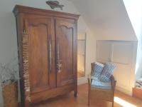 a large wooden cabinet and a chair in a room at Maison typique bretonne a 5 min de la plage a pied in Crozon