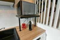 a microwave on a stand with a television on a counter at Au Fil du Temps in Sélestat