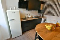 a kitchen with a wooden table and a white refrigerator at Au Fil du Temps in Sélestat