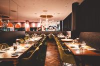 a restaurant with long tables and chairs and a chandelier at Kameha Grand Bonn in Bonn