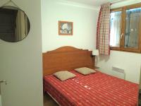 Schlafzimmer mit einem Bett mit einer roten Decke und einem Spiegel in der Unterkunft Appartement Albiez-Montrond, 2 pièces, 4 personnes - FR-1-618-1 in Albiez-Montrond