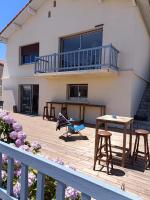 a house with a deck with a table and stools at Maison Mimizan plage in Mimizan