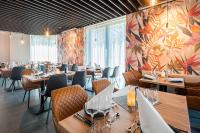 フランクフルト・アム・マインにあるBest Western Hotel Airport Frankfurtの木製のテーブルと椅子、花の壁があるレストラン
