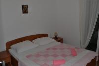 a bedroom with a bed with pink slippers on it at Apartments with a parking space Grebastica, Sibenik - 13365 in Bašelovići