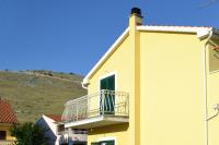 a yellow building with a balcony and a hill at Apartments with a parking space Grebastica, Sibenik - 13365 in Bašelovići