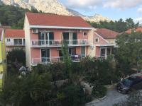 a pink house with a mountain in the background at Apartments with a parking space Orebic, Peljesac - 15086 in Orebić