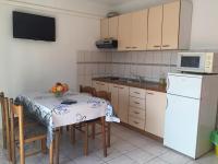 a kitchen with a table and a white refrigerator at Apartments with a parking space Orebic, Peljesac - 15086 in Orebić