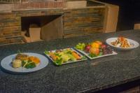 three plates of food on a counter with fruits and vegetables at Manong Game Lodge in Gaborone