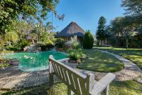 a bench in front of a house with a pool at Manong Game Lodge in Gaborone