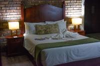 a bedroom with a large bed with two lamps at Manong Game Lodge in Gaborone