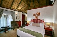 a bedroom with a bed and a chair in a room at Manong Game Lodge in Gaborone