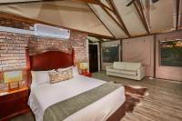 a bedroom with a bed and a brick wall at Manong Game Lodge in Gaborone