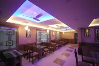 a dining room with tables and chairs and purple lighting at North Centre in Cochin