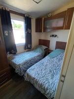 two beds in a small room with a window at La Chanterie Agréable Mobil-Home Résidentiel Normand in Saint-Pair-sur-Mer