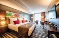 a hotel room with a large bed and a desk at Leonardo Royal Hotel Ulm in Ulm