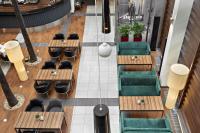 Een bovenaanzicht van een restaurant met houten tafels en groene stoelen. bij Hotel Moderno Poznań in Poznań