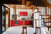 a kitchen with red cabinets and a counter with stools at Kaz Bois Blanc, classée 3 étoiles - Vue mer - Les Avirons in Les Avirons