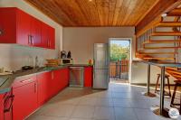 a kitchen with red cabinets and a wooden ceiling at Kaz Bois Blanc, classée 3 étoiles - Vue mer - Les Avirons in Les Avirons