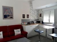 a living room with a red couch and a kitchen at Concarneau studio avec terrasse in Concarneau