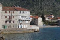 a group of buildings on a beach next to the water at Apartments and rooms by the sea Komiza, Vis - 2431 in Komiža