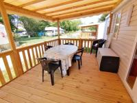 a wooden deck with a table and chairs on a porch at MOBIL-HOME NEUF 6 PERSONNES réservation du samedi au samedi en juillet et août in Urt