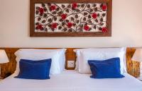 a bedroom with a bed with blue pillows and a painting on the wall at Barra do Piuva Porto Hotel in Ilhabela